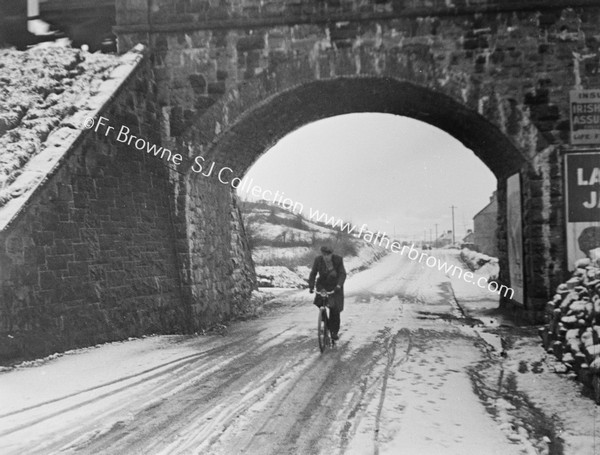 CYCLIST UNDER BRIDGE IN SNOW